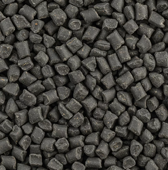 Close-up of many small, irregular black plastic pellets tightly packed together, filling the entire frame.