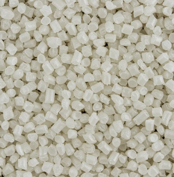 Close-up of many small, off-white plastic pellets tightly packed together, filling the entire frame.